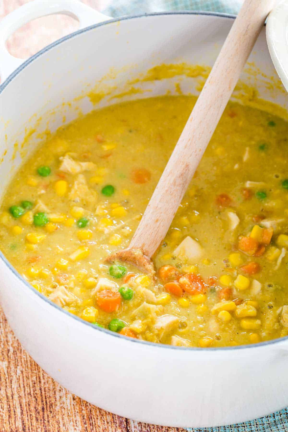 A pot of Chicken Corn Chowder with a wooden spoon in it.