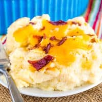 A scoop of Low Carb Cauliflower Mashed Potatoes with cheddar cheese and bacon on a plate