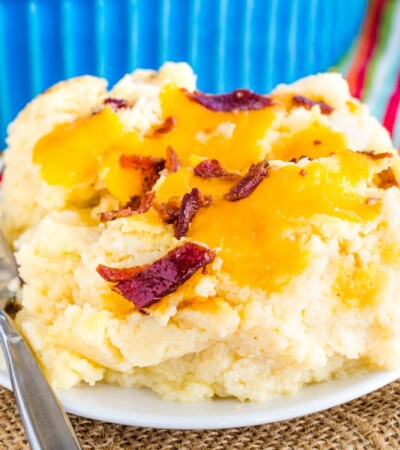 A scoop of Low Carb Cauliflower Mashed Potatoes with cheddar cheese and bacon on a plate