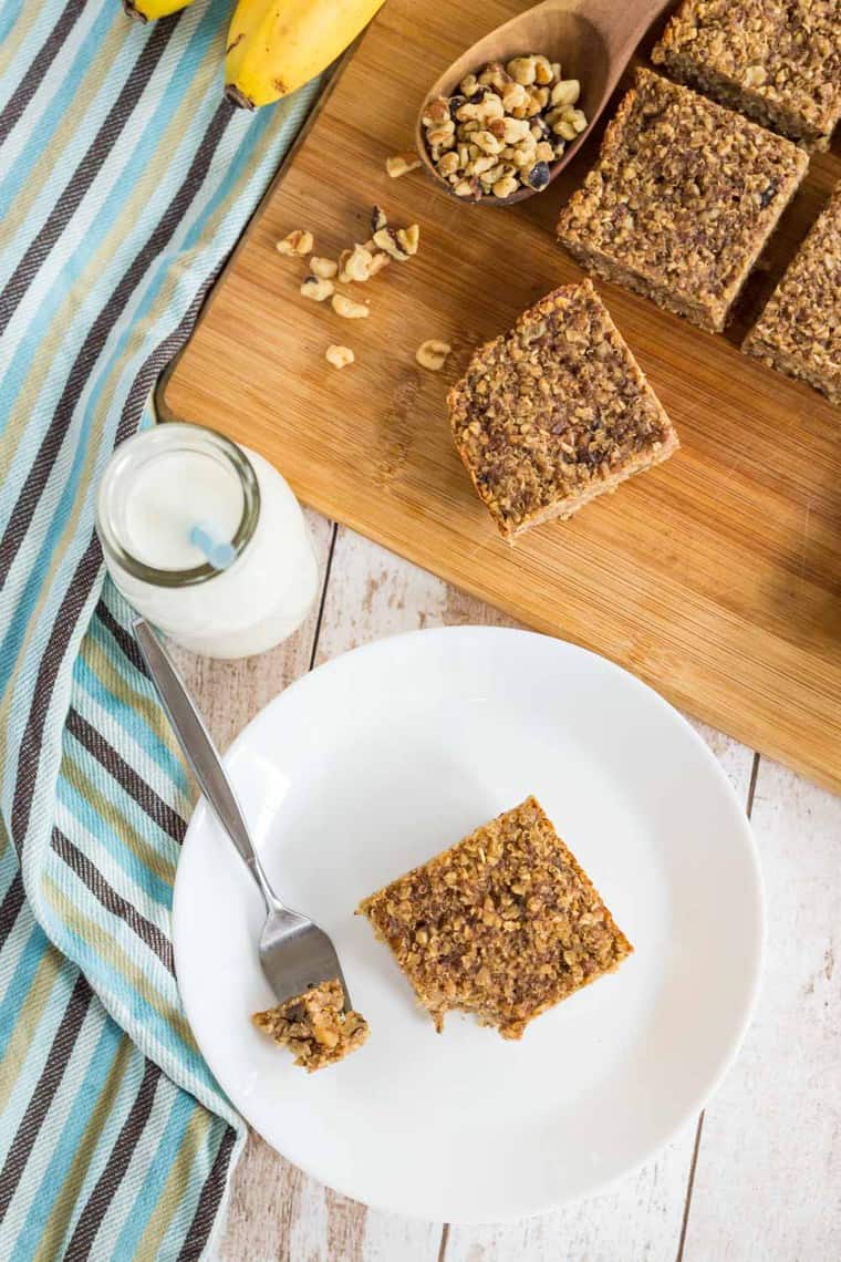 Overhead of Quinoa Oatmeal Banana Breakfast Bars on a plate and a cutting board with milk
