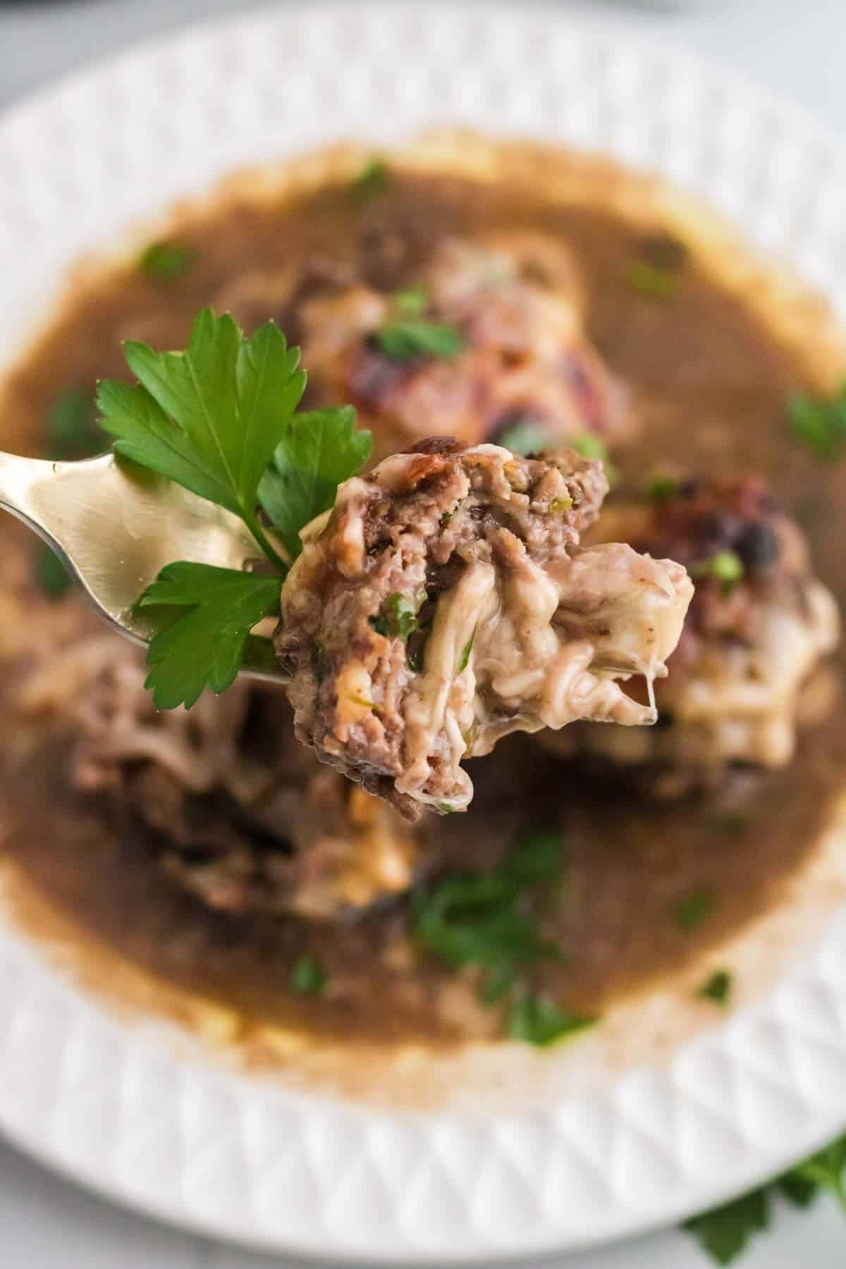 A French onion and mozzarella stuffed meatball on a fork.