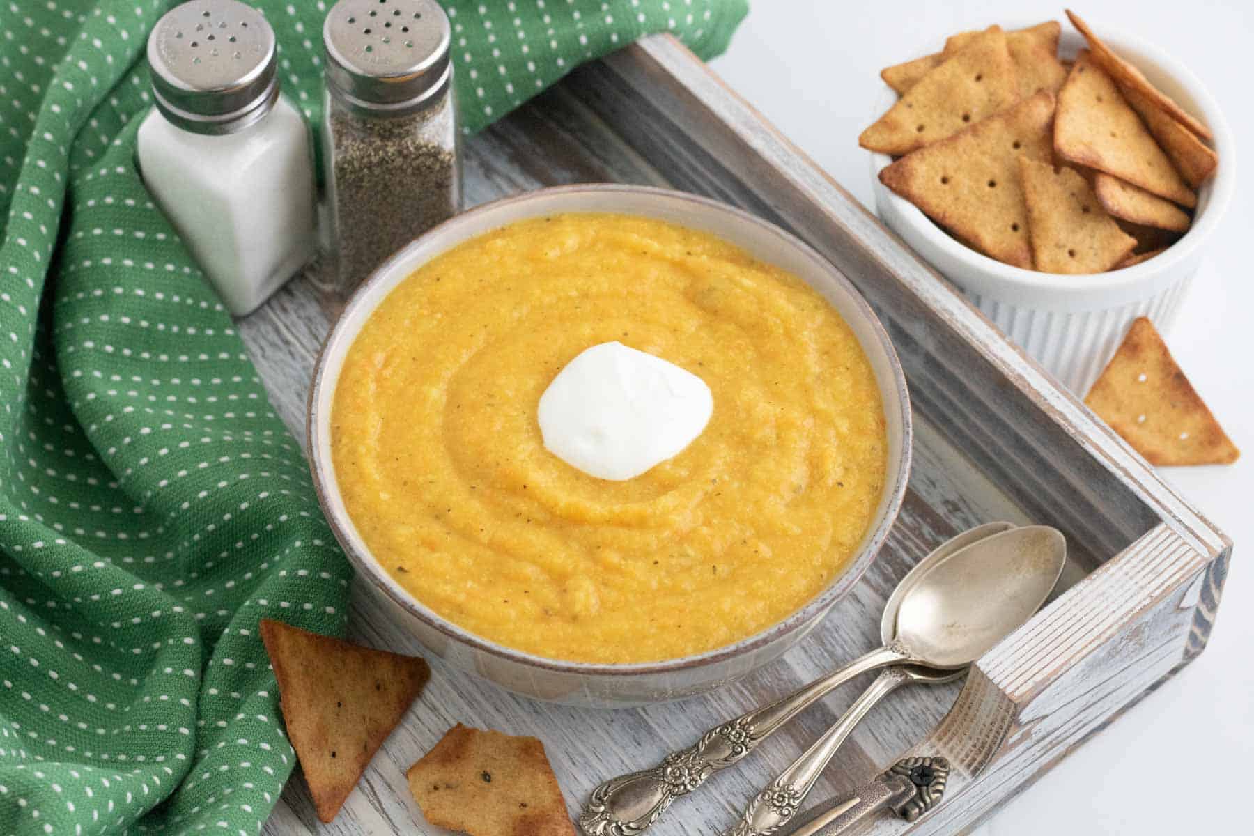 vegetable soup on a tray with spoons and crackers