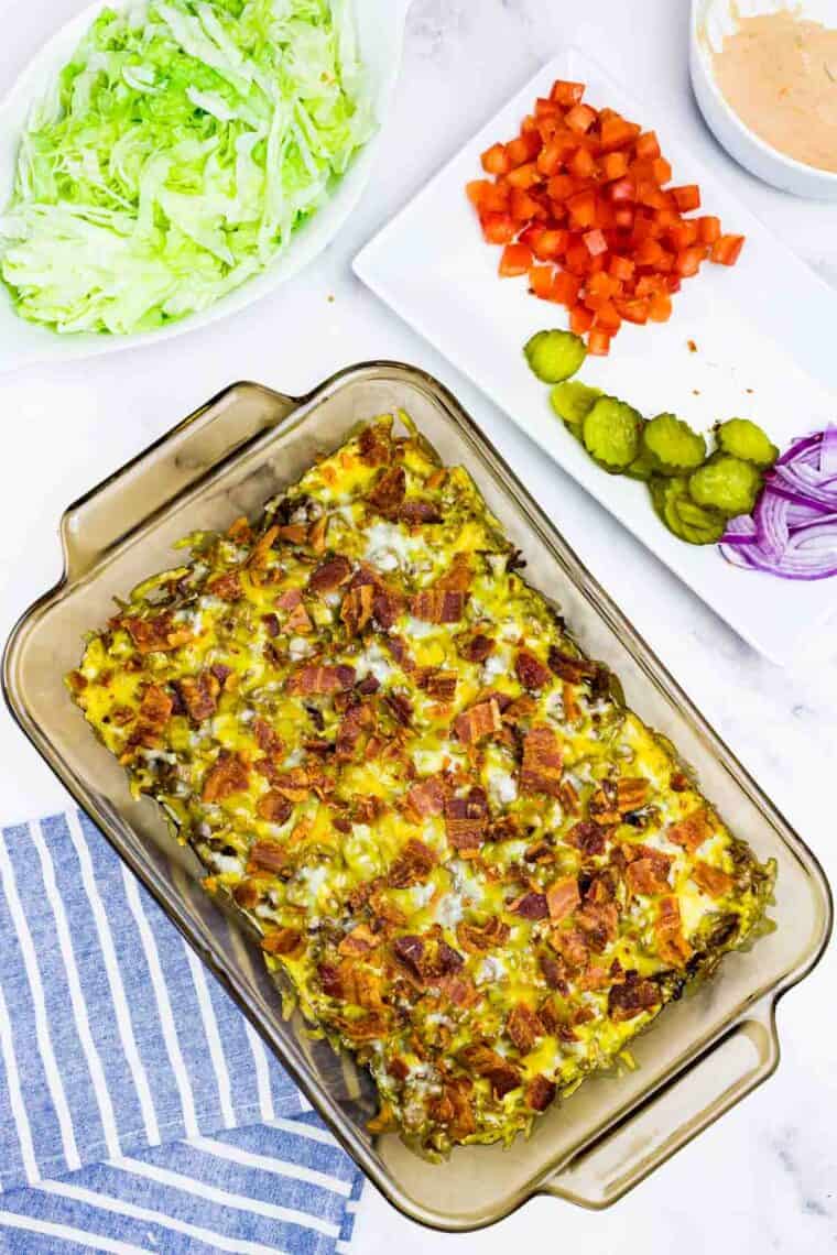 Bacon sprinkled on top of cheeseburger dip in a casserole pan