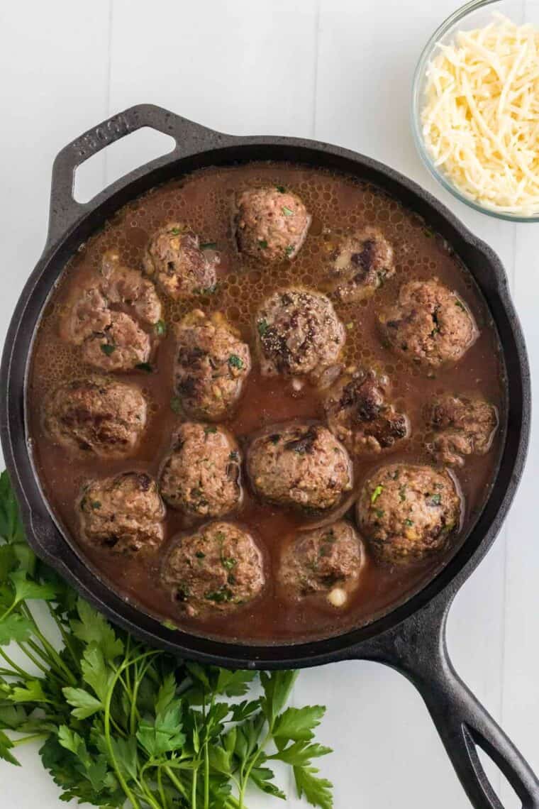 French onion meatballs are simmered in a skillet with beef sauce.