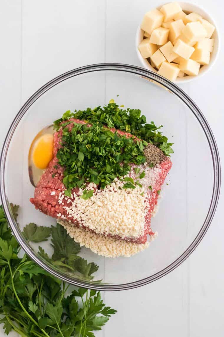 Ingredients for meatballs are added to a mixing bowl.