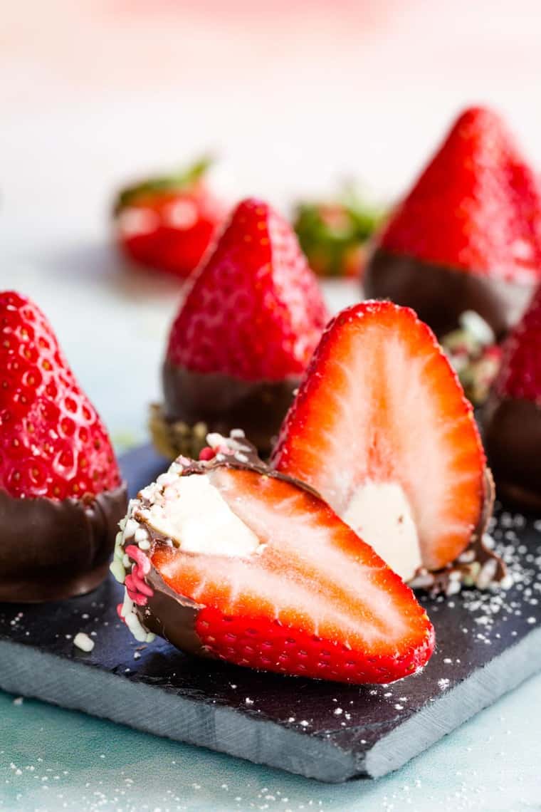 One of the cut open cheesecake stuffed strawberries dipped in chocolate