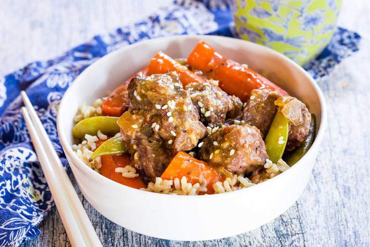 Slow Cooker Mongolian Beef Stew sprinkled with sesame seeds and white chopsticks on the side