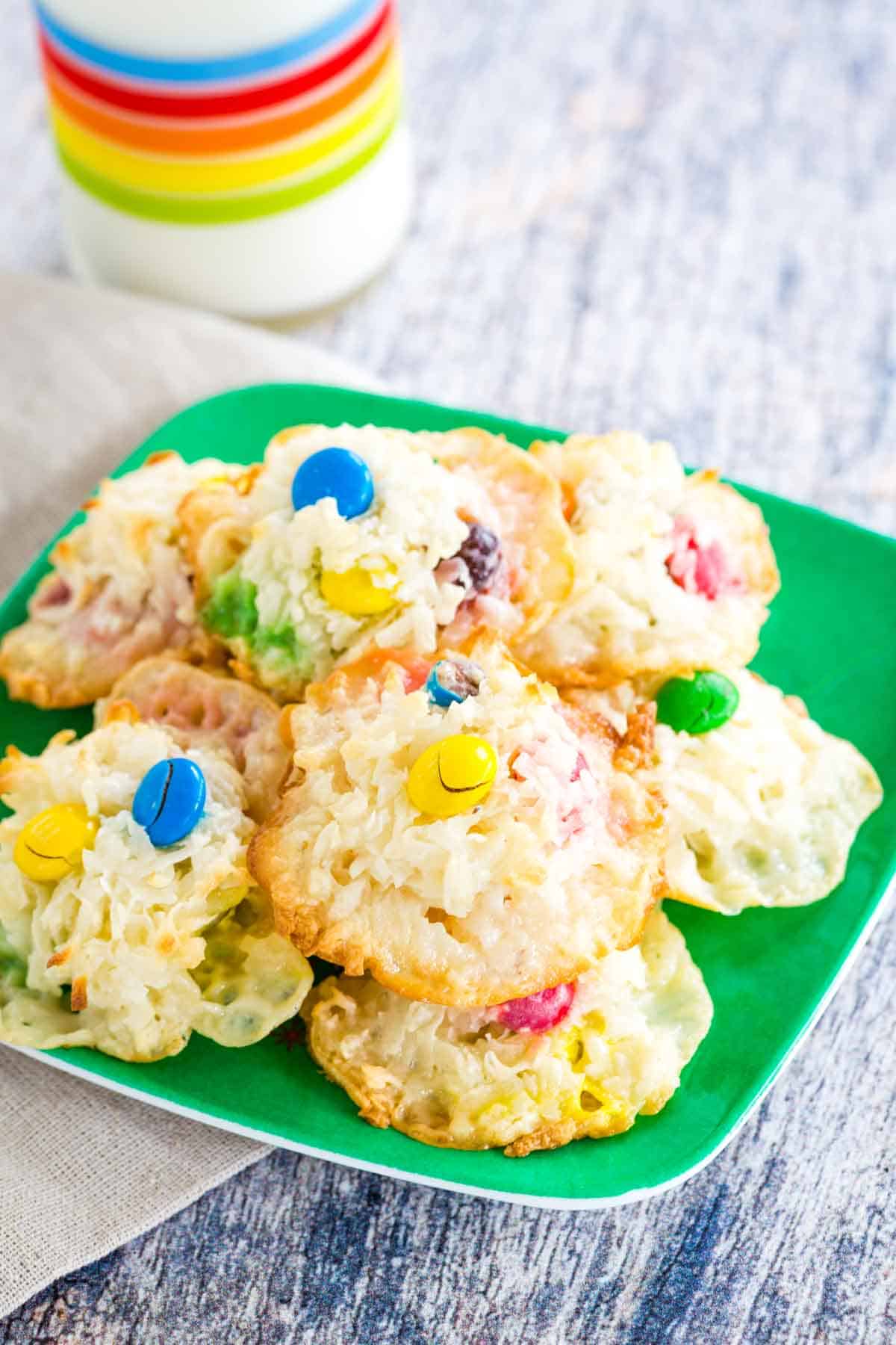 A green plate with a pile of Coconut Macaroons with M&M's.