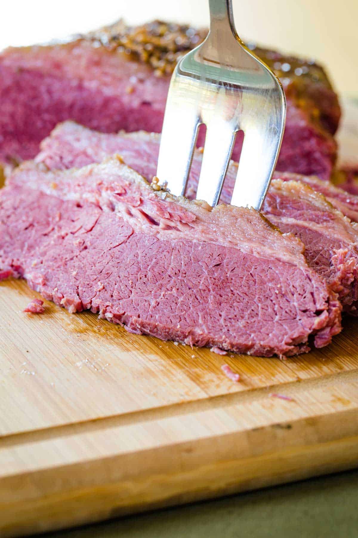 A slice of cooked beef brisket being speared with a fork.