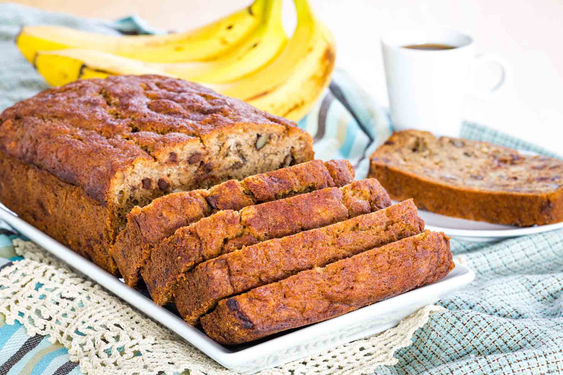 Gluten Free Banana Bread on a white platter with a slice on a plate