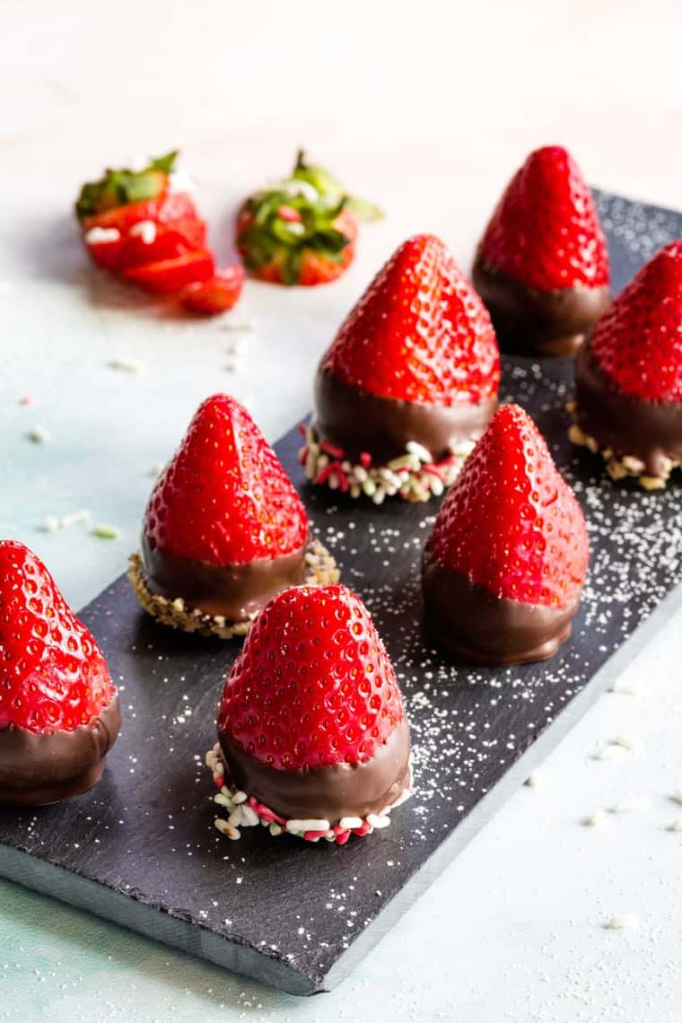 Chocolate Covered Cheesecake Stuffed Strawberries on a slate platter with powdered sugar