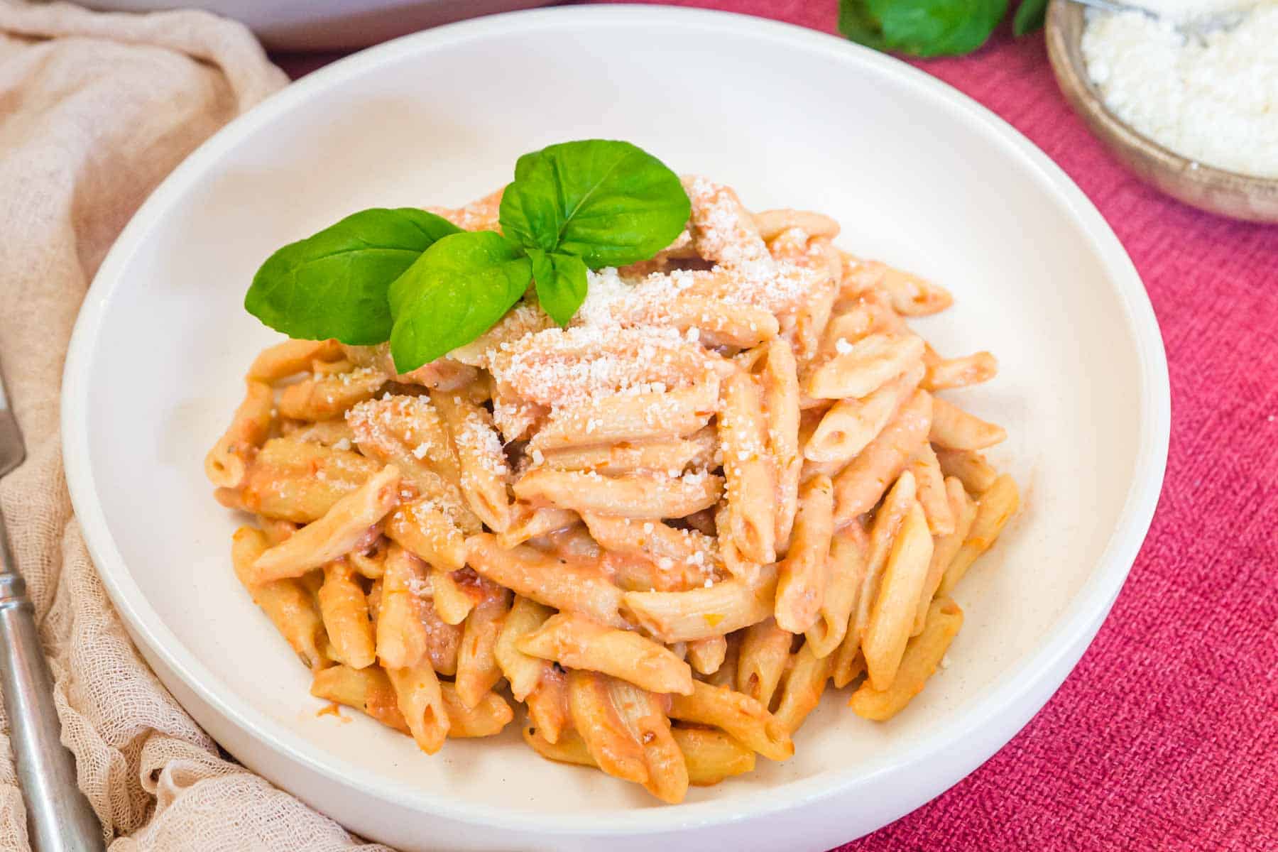 A white bowl filled with pasta covered in vodka sauce