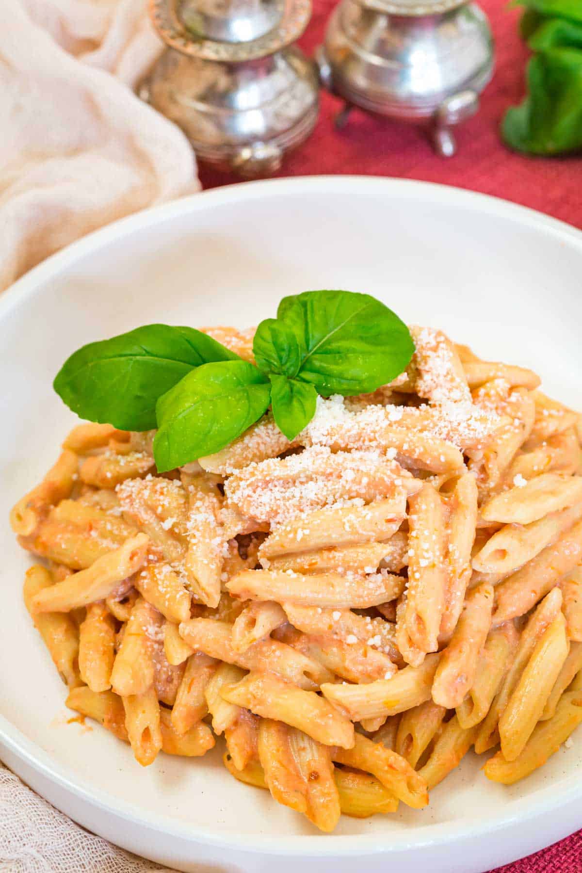 A white bowl filled with pasta covered in vodka sauce