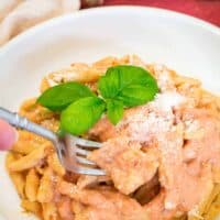 A white bowl with penne alla vodka and a fork