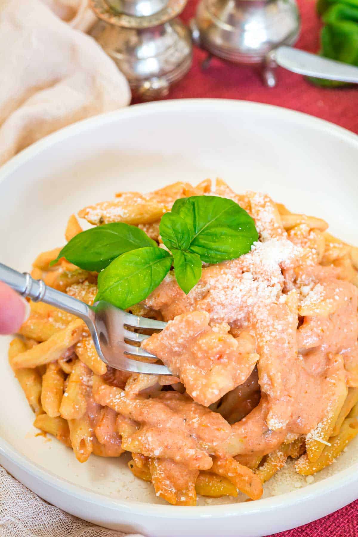 A white bowl with penne alla vodka and a fork