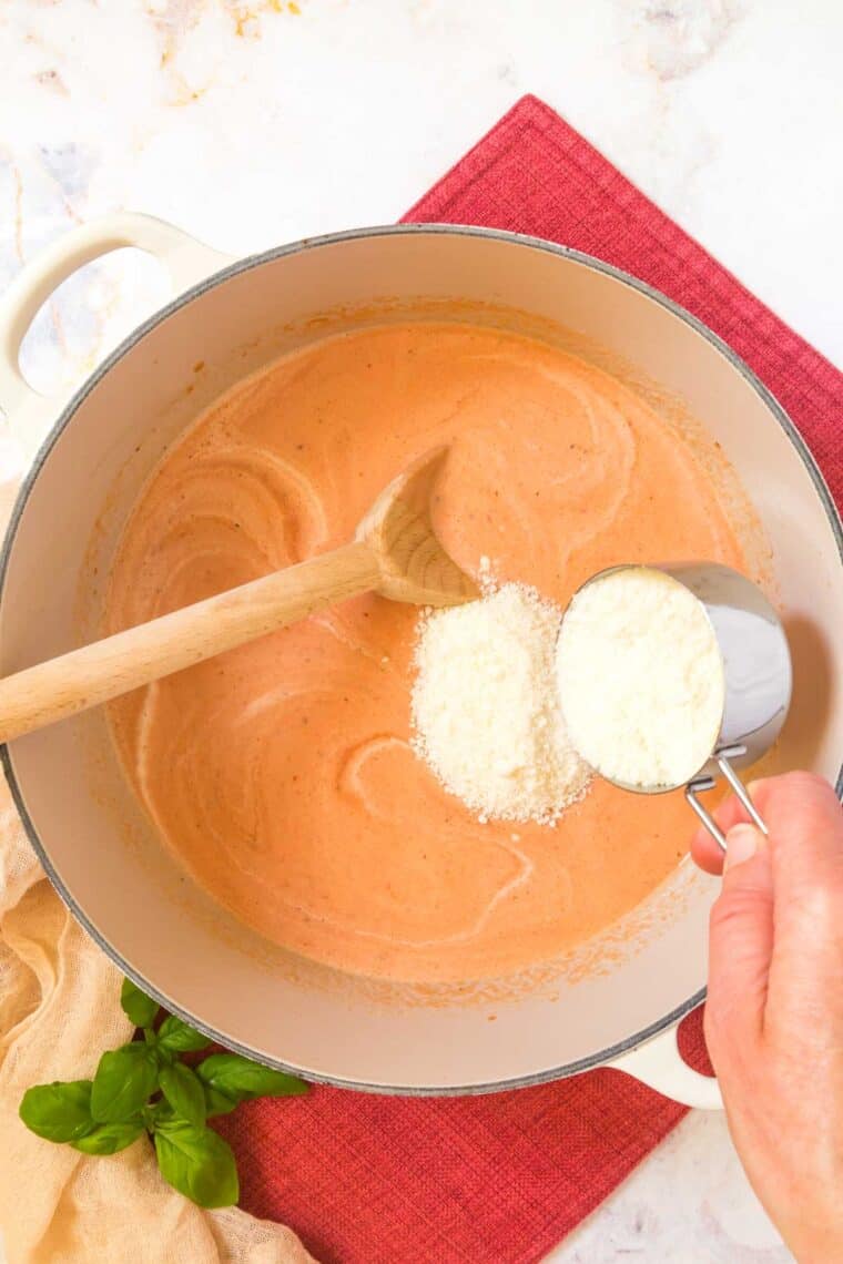 Adding cheese to vodka sauce in a pot