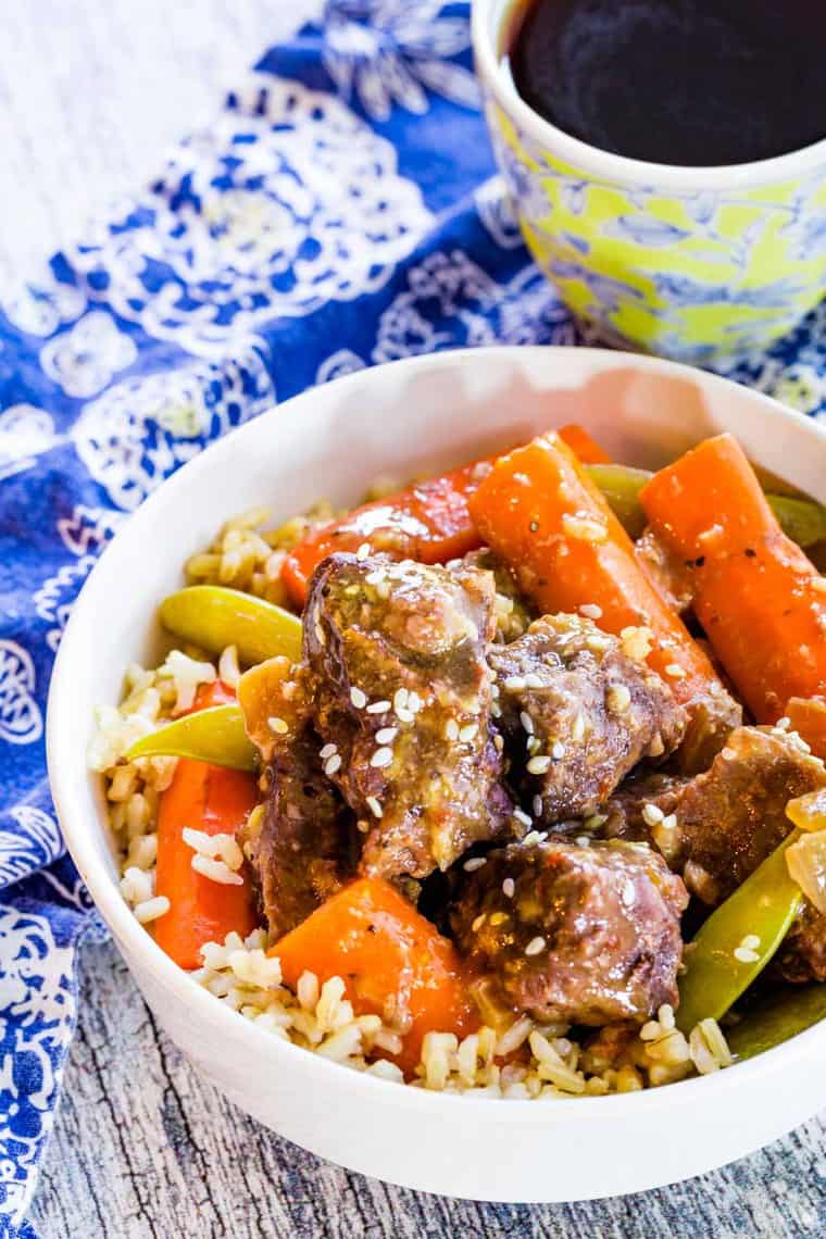 Crock Pot Mongolian Beef Stew with carrots and sugar snap peas in a bowl with rice