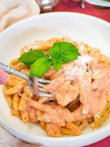 A white bowl with penne alla vodka and a fork