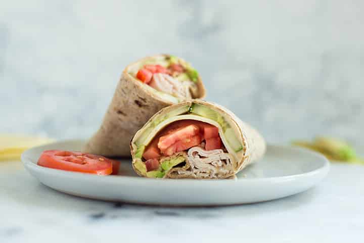 turkey hummus wrap cut in half on a plate.