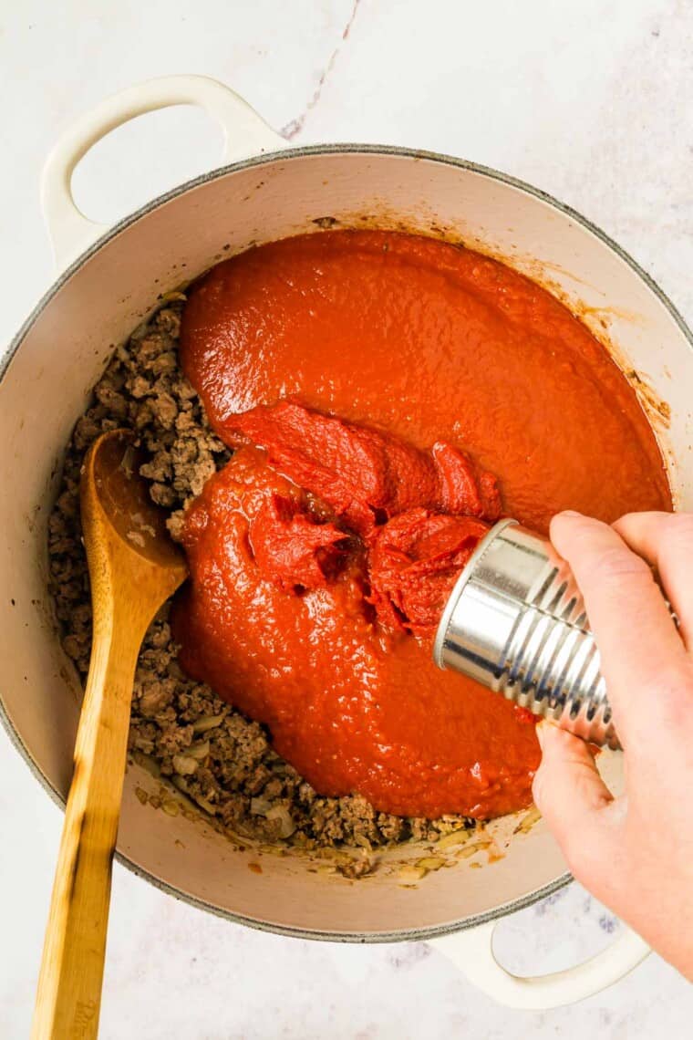 Add canned crushed tomatoes and other sauce ingredients to the pot