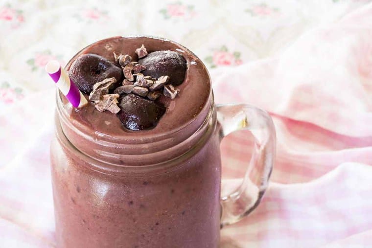 Black Forest Smoothie with cherries on top and a straw