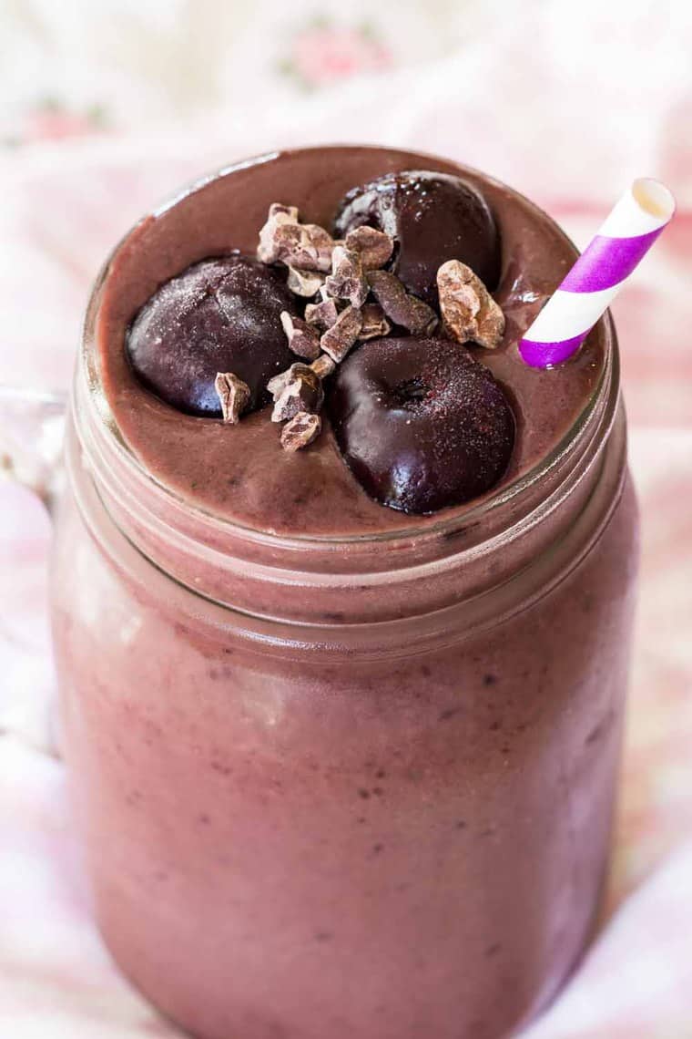Closeup of cherries and cacao nibs floating on top of a Black Forest Smoothie