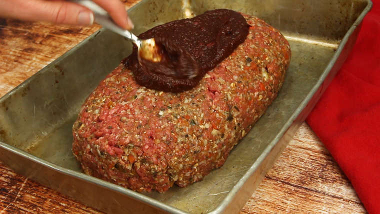 Spreading balsamic ketchup glaze over top of meatloaf before baking