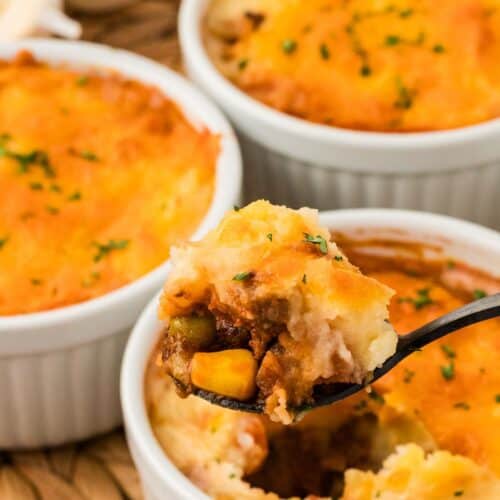 Three mini shepherd's pies, one with a spoon in it