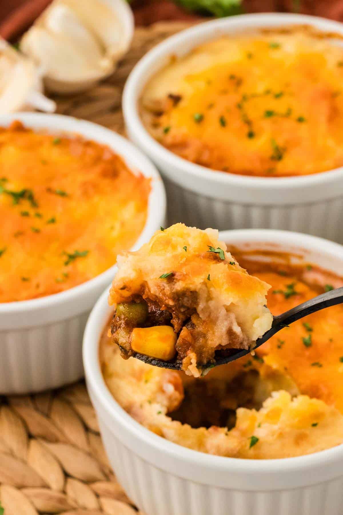 Three mini shepherd's pies, one with a spoon in it 