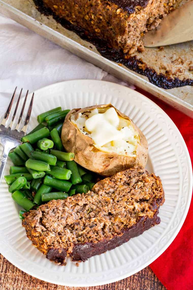 Overhead of a slice of Roasted Veggie Balsamic Meatloaf on a plate with a baked potato and green beans