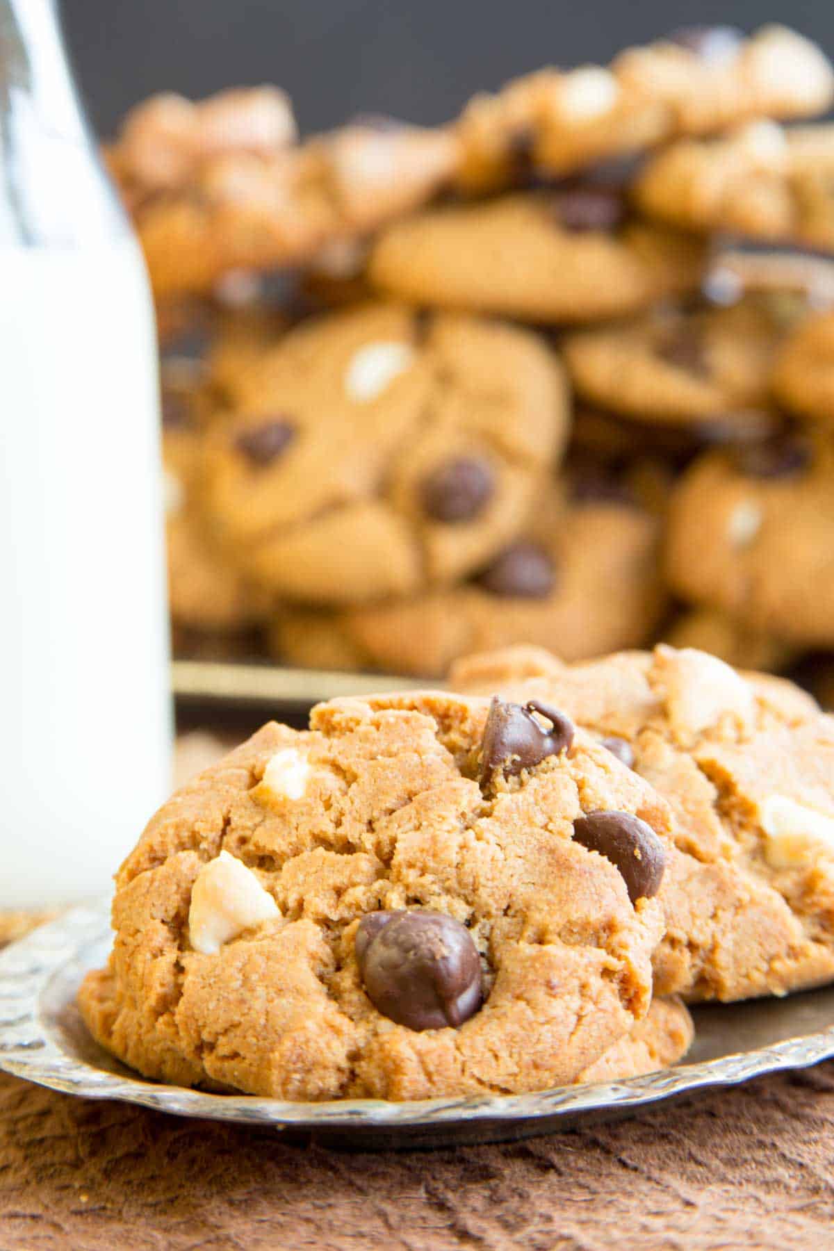 Flourless Peanut Butter Cookies with chocolate chips on a silver plate with a bottle of milk and more cookies behind it.