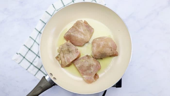 Brown seasoned chicken breasts in melted butter in a skillet