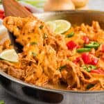 A wooden spoon serving chicken enchilada skillet