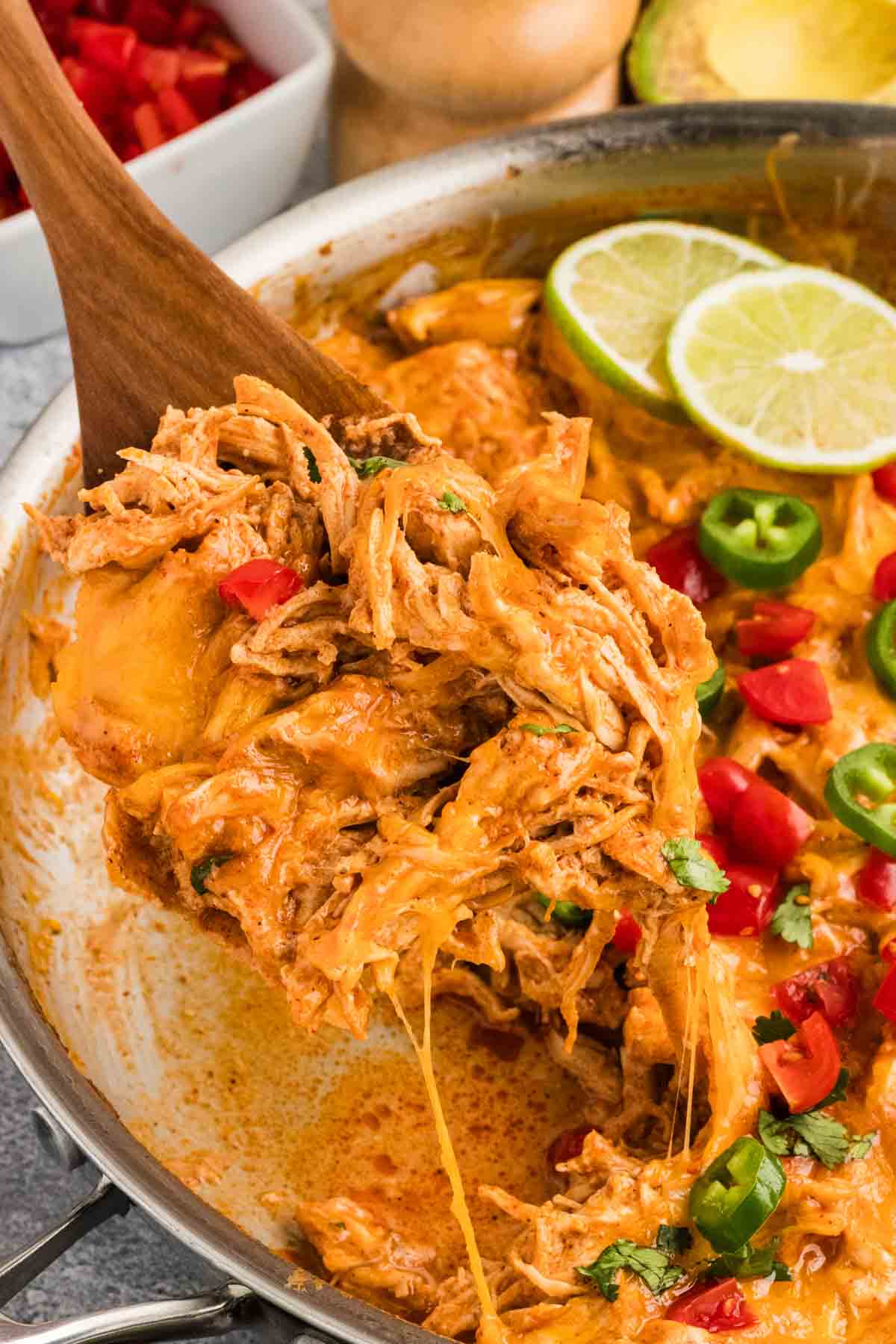 A wooden spoon serving a chicken enchilada skillet dinner