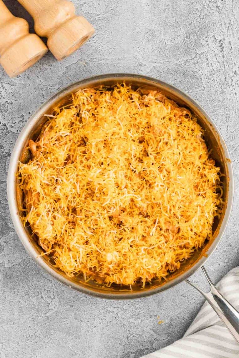 Shredded cheese on rice in a skillet