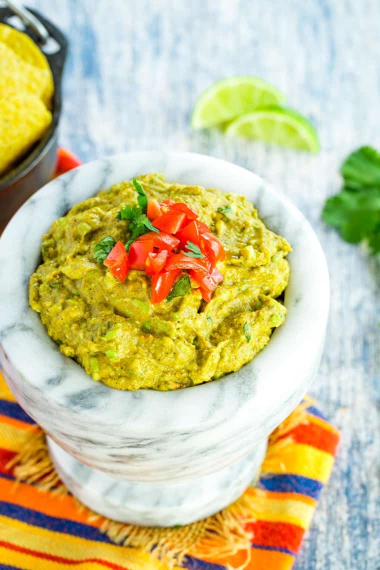 Easy Guacamole in a marble bowl with tomatoes on top