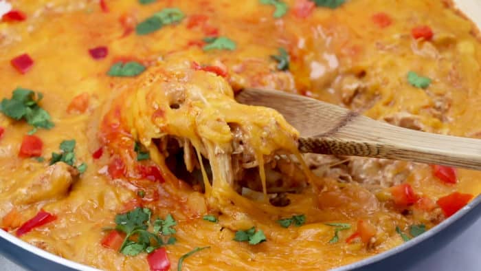 Spoon cheesy chicken enchiladas out of the skillet
