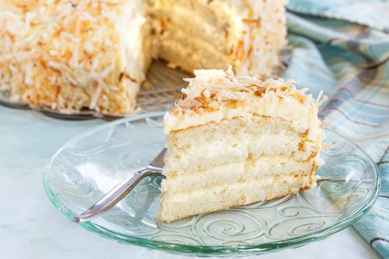 Gluten free white cake with coconut filling and frosting on a glass plate