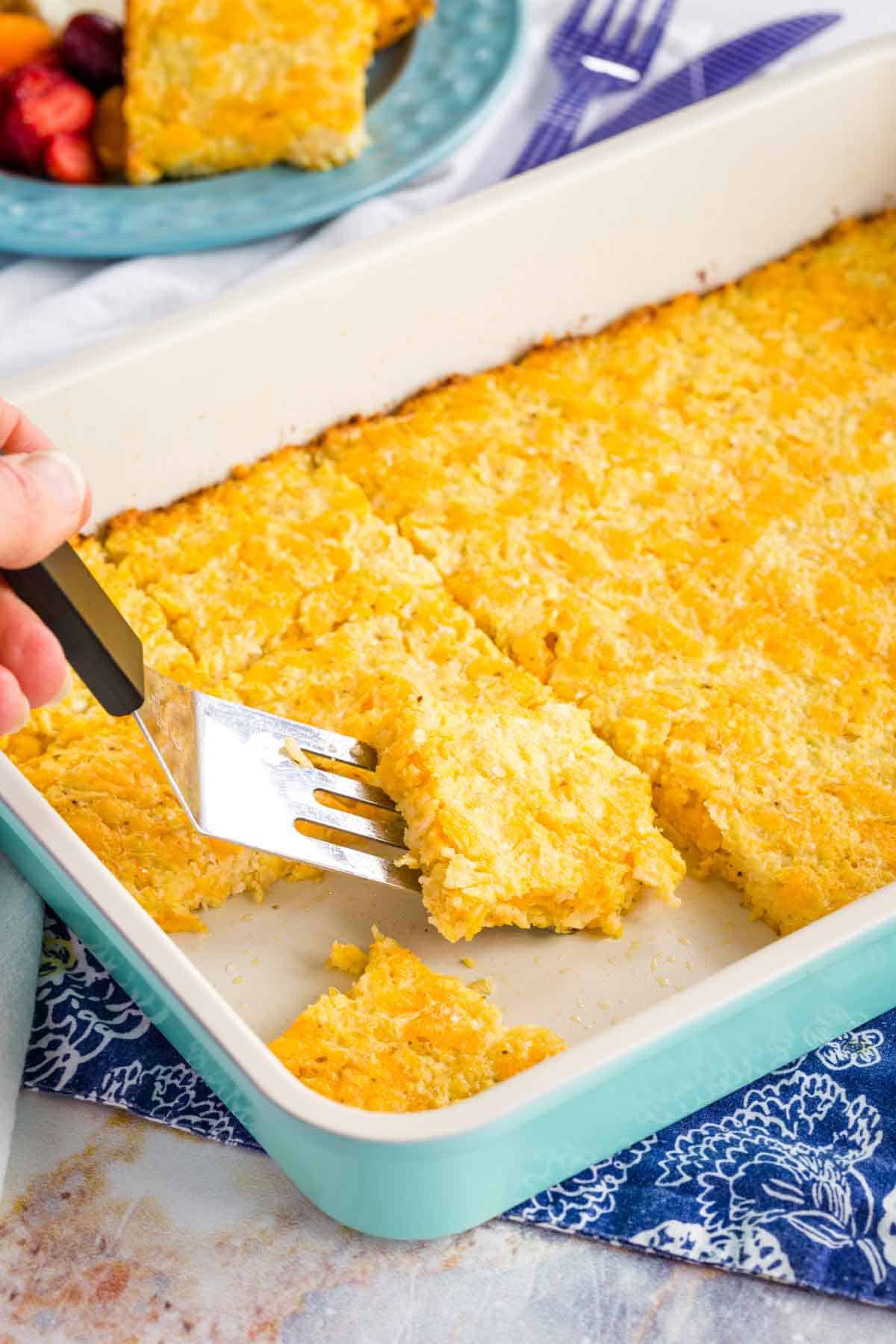 Serving Cauliflower Hash Browns Breakfast Bake from a rectangular pan with a spatula.