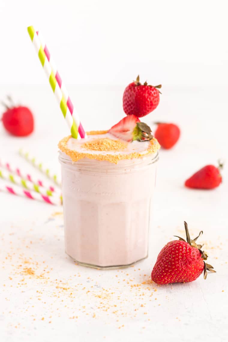 Cheesecake Strawberry Smoothie in a glass with strawberries for garnish and striped straws