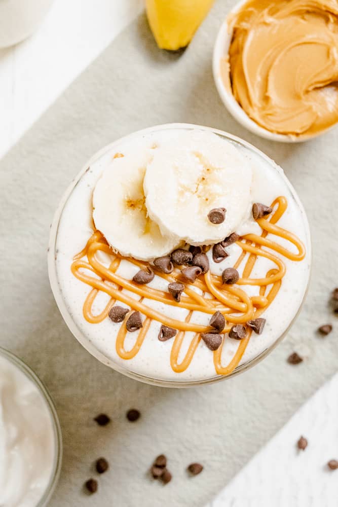 Overhead of Peanut Butter Smoothie with chocolate chips, banana slices, and drizzled peanut butter on top