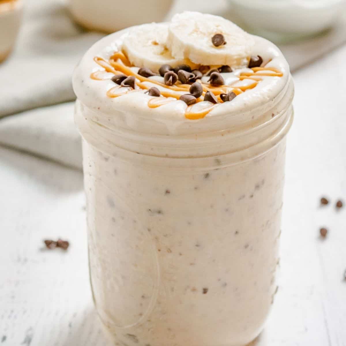 A peanut butter smoothie with chocolate chips in a glass jar.