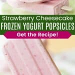 A stack of three pink popsicles on a pale green platter and one being held up divided by a green box with text overlay that says "Strawberry Cheesecake Frozen Yogurt Popsicles" and the words "Get the Recipe!".