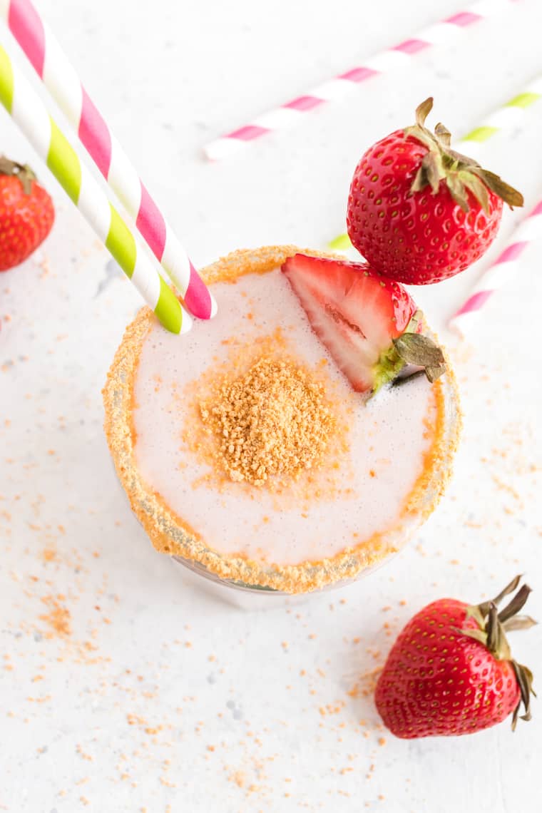 Strawberry Cheesecake Smoothie in a glass with graham cracker crumbs on the rim