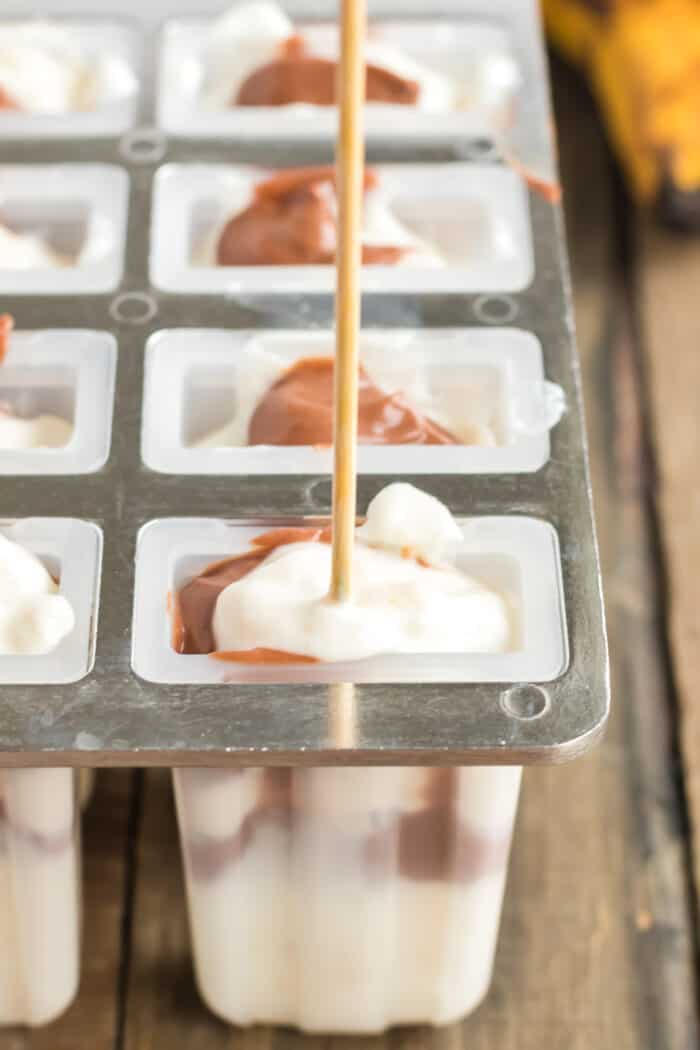 Putting banana yogurt and nutella yogurt mixtures into popsicle molds