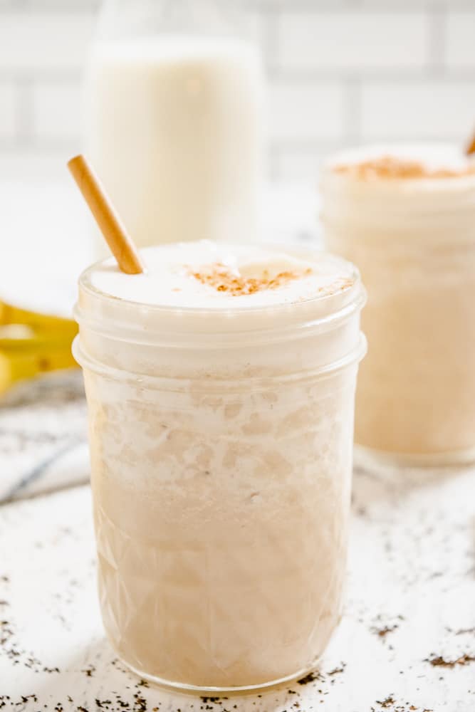 Chai Smoothie in a glass jar with banana and cinnamon sprinkled on top