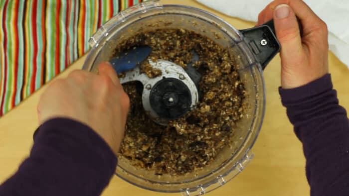 Using a spatula to stir Chunky Monkey Energy Balls mixture in food processor