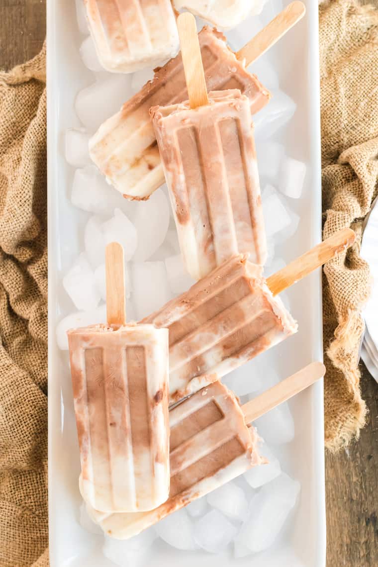 Nutella Banana Yogurt Popsicles on a white platter with ice cubes