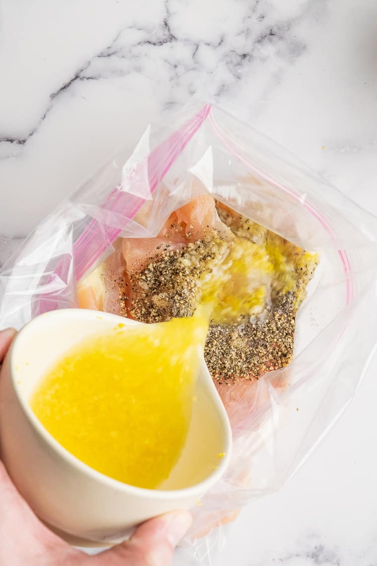 Pouring lemon juice over chicken in a plastic bag