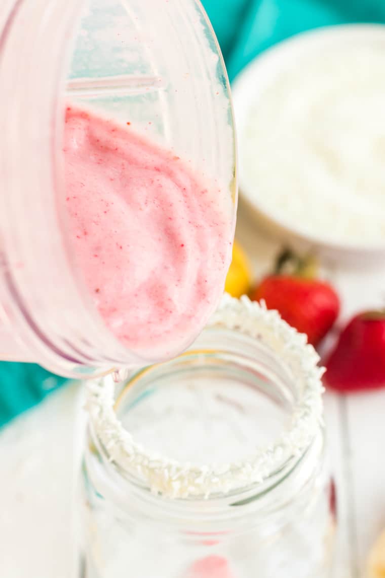 Pouring the finished smoothie in a coconut-rimmed glass